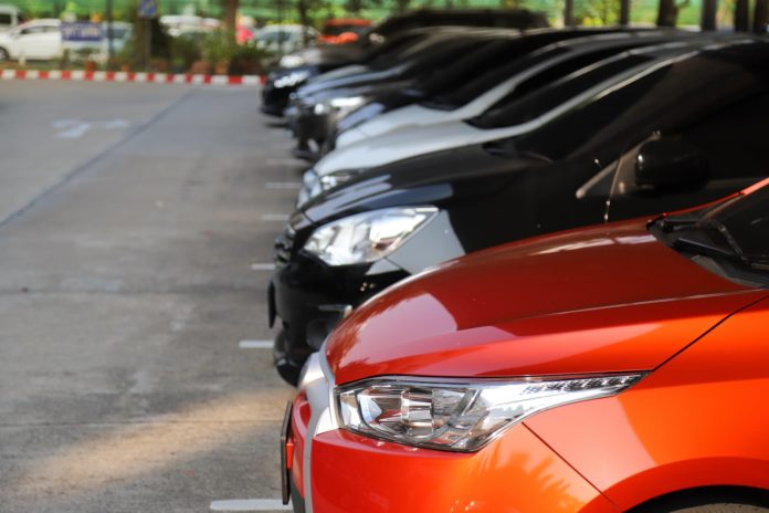 Closeup of front side of red car with other cars parking in parking area.