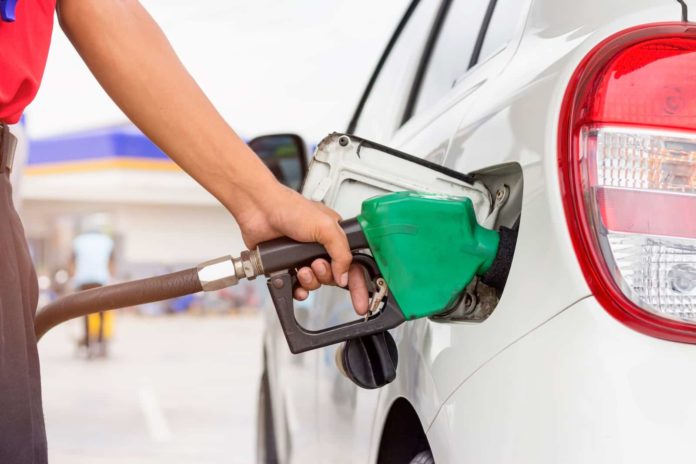 Pumping gas at gas pump. Closeup of man pumping gasoline fuel in car at gas station